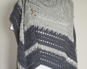 May include: A two-toned crochet shawl featuring light grey and dark charcoal grey yarn. The garment displays a textured pattern with openwork stitches and bobbles, secured at the neckline with two small wooden toggle buttons on the upper edge.