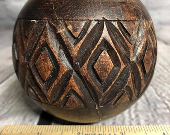 May include: A round, wooden box with a carved geometric pattern. The box is dark brown with lighter brown accents. A wooden ruler is in the foreground, with the text "MADE IN U.S.A." and "WESTERN KENTUCKY ENERGY".