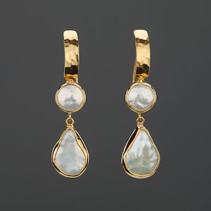 May include: A pair of gold earrings with a teardrop-shaped pearl and a round pearl. The earrings are made of hammered gold and have a simple, elegant design.