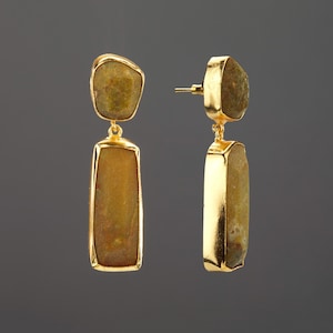 May include: A pair of drop earrings featuring gold-toned metal settings and irregular, textured, brownish-yellow stones. Each earring consists of a smaller, rounded top stone and a larger, rectangular bottom stone suspended by a small gold link.