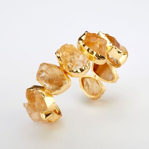May include: A gold bracelet featuring a series of faceted, light brown, natural stones. The stones are set in gold and arranged in a staggered pattern.