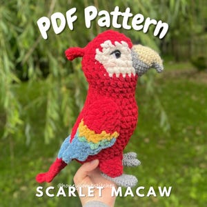 May include: A handmade, plush scarlet macaw parrot. The bird is primarily red with white, blue, yellow, and green accents. The text "PDF Pattern" and "Scarlet Macaw" are displayed on the image.