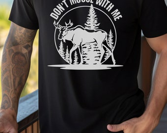 以下が含まれることがあります： 「Don't Moose With Me」というテキストと、森の中にいるヘラジカの白いグラフィックが描かれた黒いTシャツ。