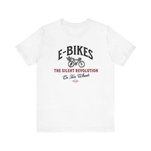 Puede incluir: Camiseta blanca con un gráfico negro de una bicicleta eléctrica con el texto "E-Bikes The Silent Revolution On Two Wheels USA"