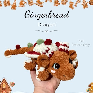 Könnte beinhalten: Häkelmuster für einen Lebkuchen-Drachen als PDF. Ein brauner und weißer gehäkelter Drache mit Zuckerstangen- und Lebkuchendetails.  Nur PDF-Muster.