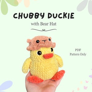 May include: A crochet pattern for a yellow duck wearing a brown bear hat. The pattern is available as a PDF download and is titled "Chubby Duckie with Bear Hat".
