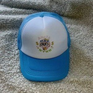 Könnte beinhalten: Eine blaue und weiße Trucker-Kappe mit einer Comicfigur, die eine Brille trägt, und dem Text "ANITA MAX WYNN" auf der Vorderseite.