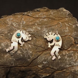 May include: A pair of silver earrings with turquoise stones. Each earring features a stylised figure of a Native American dancer.