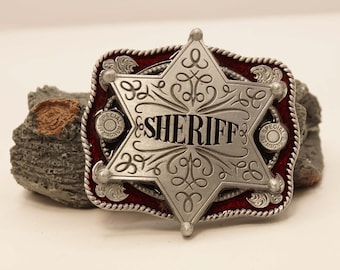Western belt buckle of a sheriff star on red shield