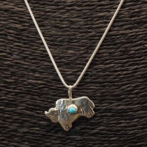 May include: A silver necklace with a turquoise stone buffalo pendant.