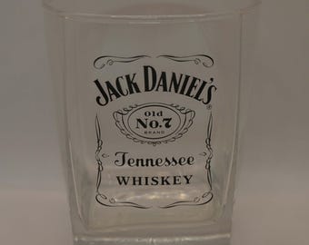 May include: A clear glass tumbler with a black Jack Daniel's logo. The logo features the text "Jack Daniel's", "Old No. 7 Brand", and "Tennessee Whiskey".