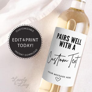 Peut inclure: Bouteille de vin blanc avec une étiquette imprimable qui dit "Pairs well with a Custom Text Your message here". L'étiquette est blanche avec du texte noir et une icône de cœur.