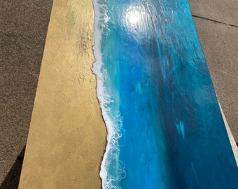 May include: Abstract painting depicting an ocean scene with a golden sand beach and blue water with white foam waves.