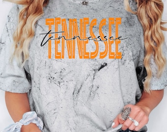 Puede incluir: Una camiseta blanca con un patrón de tie-dye y texto naranja que dice "Tennessee" en una fuente retro.