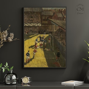 May include: Framed vintage artwork depicting a soccer match in progress. Players in red and blue uniforms are on a green field, with a crowd in the background. The artwork is framed in black.