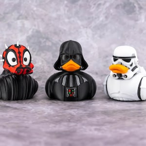 May include: Three rubber duck toys styled as Star Wars characters: Darth Maul, Darth Vader, and a Stormtrooper. The Darth Maul duck is red and black with white horns. Darth Vader is black with a black helmet. The Stormtrooper duck is white with a black helmet.