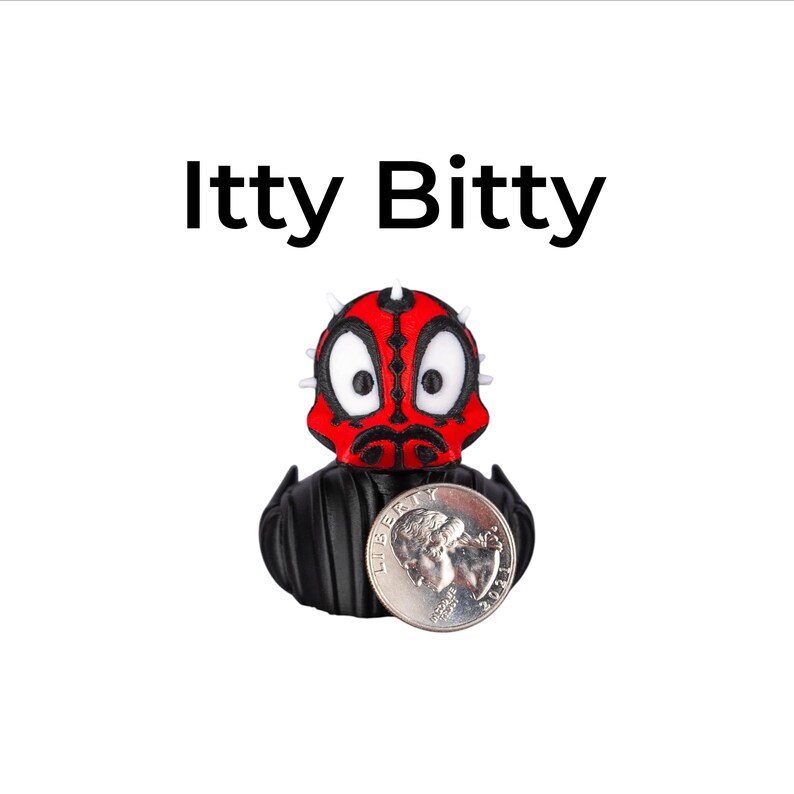 May include: A small, black and red figurine of a character with a quarter coin next to it. The figurine has a red face with black markings and white eyes. The text "Itty Bitty" is above the figurine.