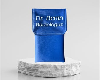 Può includere: Una custodia in pelle blu con il testo "Dr. Bertin Radiologue" in lettere bianche.