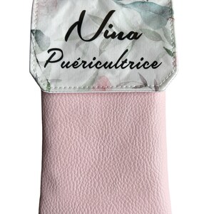 May include: A pink leather phone case with a floral pattern and the text "Nina Pu&eacute;riculture" on the flap.