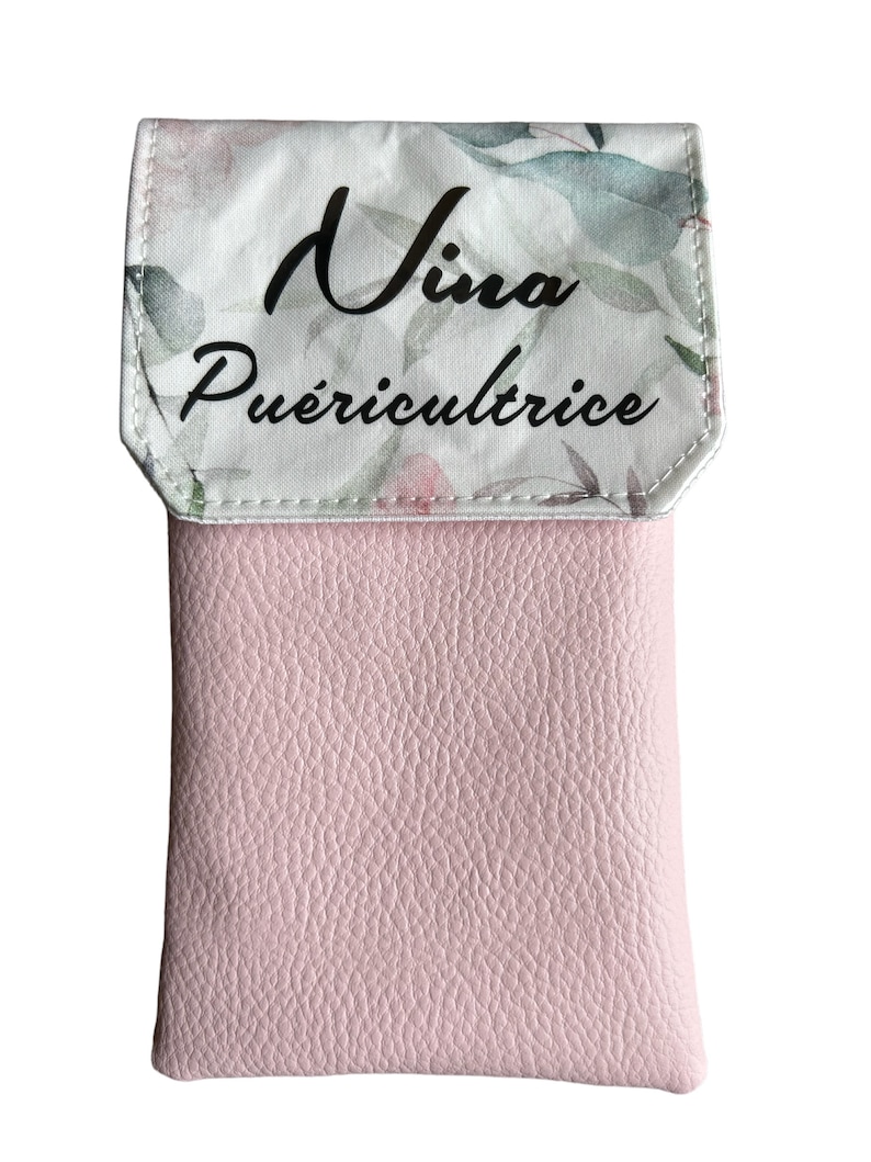 May include: A pink leather phone case with a floral pattern and the text "Nina Pu&eacute;riculture" on the flap.