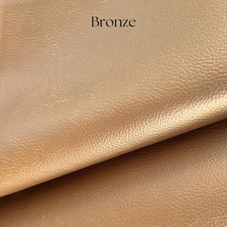 May include: A close-up of a piece of faux leather in a bronze color. The leather has a textured surface.