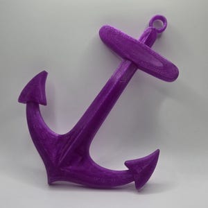 May include: A purple plastic anchor with a loop at the top. The anchor is a nautical themed decoration.