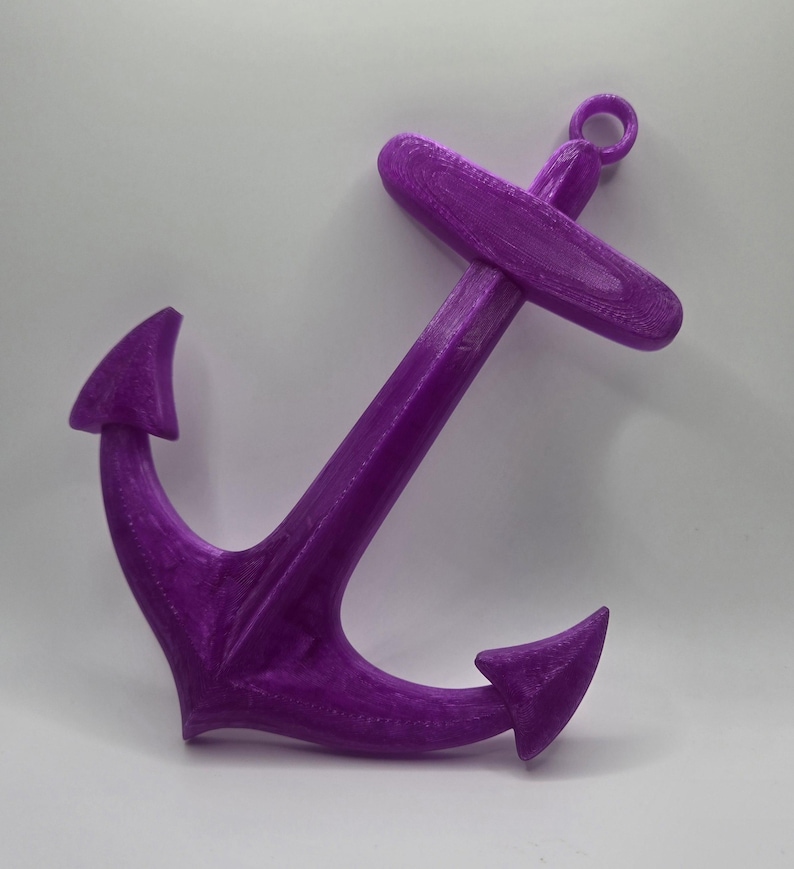 May include: A purple plastic anchor with a loop at the top. The anchor is a nautical themed decoration.