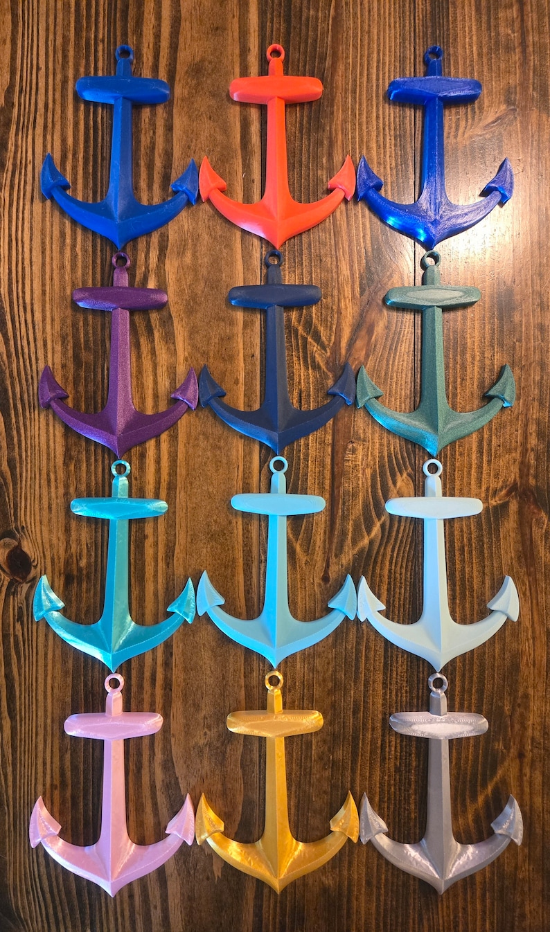 May include: Twelve different colored 3D printed anchor ornaments. The anchors are all the same size and shape, but are painted in different colors, including blue, red, purple, green, teal, light blue, pink, gold, and silver.