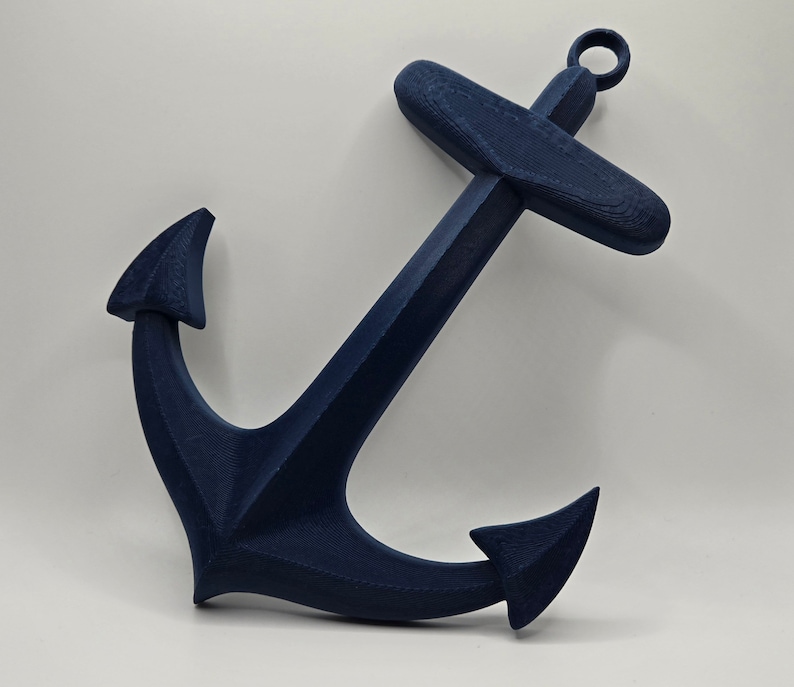May include: A dark blue anchor made of plastic. The anchor has a loop at the top and two points at the bottom.