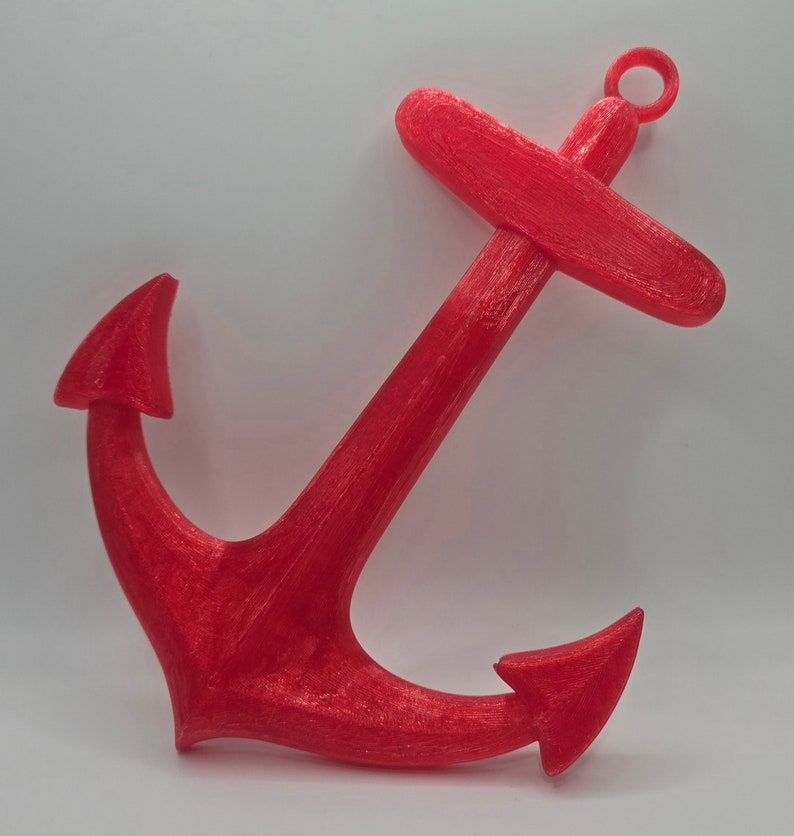 May include: A bright red anchor made of plastic. The anchor has a loop at the top and two points at the bottom.