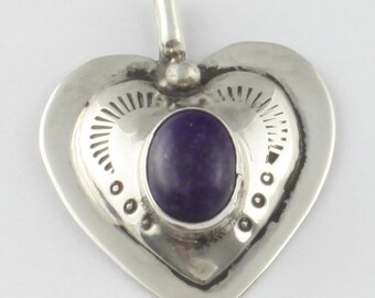 May include: Sterling silver heart pendant with a purple stone set in the center. The pendant has a detailed design around the stone.