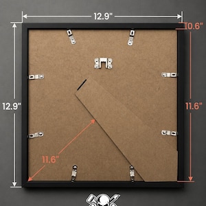 Puede incluir: Un marco de fotos negro, de 32,8 cm cuadrados, con una profundidad de 26,9 cm y una diagonal de 29,5 cm. La parte trasera presenta un respaldo de cart&oacute;n, clips met&aacute;licos y un soporte. El logotipo de VDB Vinyls es visible en la parte inferior.