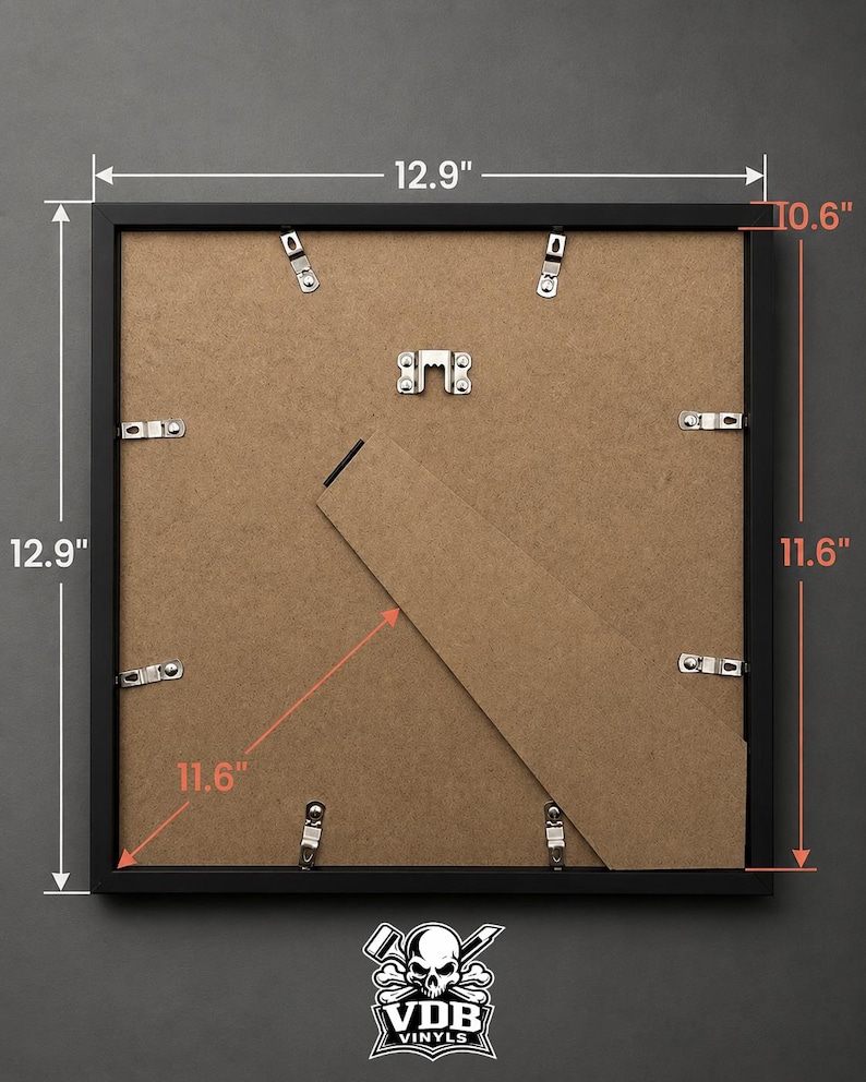 Puede incluir: Un marco de fotos negro, de 32,8 cm cuadrados, con una profundidad de 26,9 cm y una diagonal de 29,5 cm. La parte trasera presenta un respaldo de cart&oacute;n, clips met&aacute;licos y un soporte. El logotipo de VDB Vinyls es visible en la parte inferior.