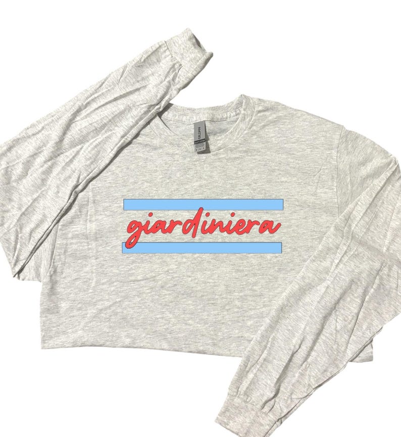 Puede incluir: Una camiseta gris de manga larga con la palabra "giardiniera" impresa en rojo sobre una franja azul.