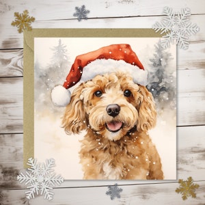 May include: A watercolour painting of a golden doodle dog wearing a red Santa hat. The dog is smiling, with its tongue visible, set against a snowy winter scene with pine trees. The image is on a square card with a kraft paper border.
