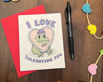 Tarjeta de felicitación divertida de San Valentín con la rana gruñona: "Me encanta tolerarte".