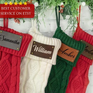 May include: Four cable-knit Christmas stockings in red, white, and green, each with a leather name tag. The red tag reads "Samantha", the white tag reads "William", the green tag reads "Amber", and the red tag reads "Amelia". The image also includes a red banner that reads "BEST CUSTOMER SERVICE ON ETSY".
