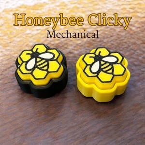 May include: Two yellow and black mechanical keycaps with a honeycomb and bee design. The keycaps are labeled "Honeybee Clicky Mechanical".