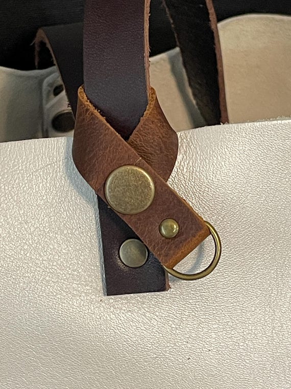 Flair holder to safely attach charms to your PLG Portland Leather Goods bags. Made with  brown full grain leather. Bronze hardware
