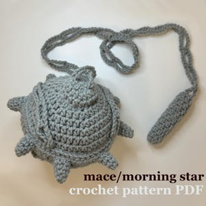 Può includere: Una mazza o stella del mattino in crochet grigio con un manico lungo. Il modello di uncinetto è disponibile per il download in PDF.