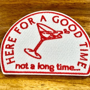 May include: Embroidered patch in a half-circle shape with the text "HERE FOR A GOOD TIME not a long time..." in red. A red martini glass is in the center. The patch is white with a red border.