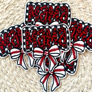 May include: Embroidered patches with the word "MAMA" in red leopard print, outlined in black and white checkered borders. Each patch features a baseball-themed bow in red and white.