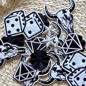 May include: A collection of black and white iron-on patches featuring various designs, including dice, diamonds, stars, and bull skulls.
