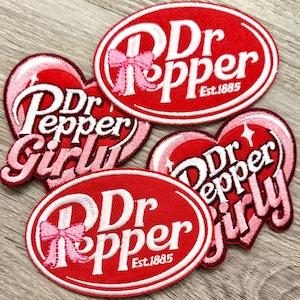May include: Embroidered patches featuring the Dr Pepper logo in red and white. Some patches have a pink bow or the words "Girly" in a heart shape. The patches are in various shapes and sizes, with the text "Est. 1885".