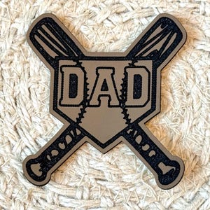 Peut inclure: Un patch en cuir marron avec un losange de baseball et deux batte de baseball croisées. Le mot "DAD" est à l'intérieur du losange en lettres noires.