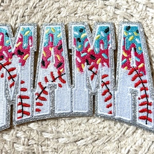 May include: Embroidered patches spelling "MAMA" in a baseball-themed design. The letters are white with a silver glitter border, featuring red baseball stitching and a pink, blue, and yellow sprinkle design.