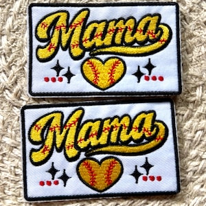 May include: Two rectangular embroidered patches on a white background. Each patch features the word Mama in yellow script with red baseball-style stitching. Below the text is a yellow heart with red stitching, flanked by black stars and red dots.