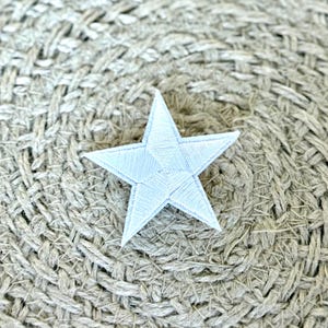 May include: A white star-shaped patch with a textured surface. The patch is on a woven background.