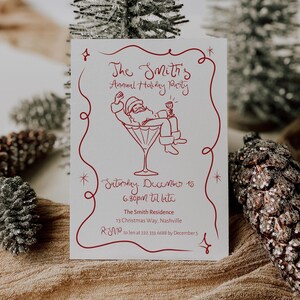 Op de afbeelding: Een witte uitnodiging voor een kerstfeest met rode tekst en een illustratie van de kerstman in een martiniglas. De tekst luidt "The Smith's Annual Holiday Party" met datum, tijd en adresgegevens.