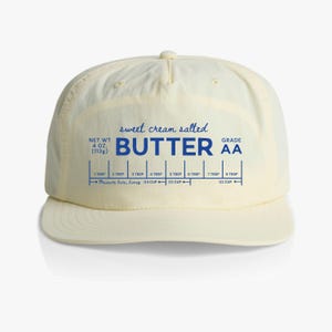 May include: A yellow baseball cap with a blue and white label that reads "sweet cream salted BUTTER AA" and includes a measurement guide for tablespoons and cups.